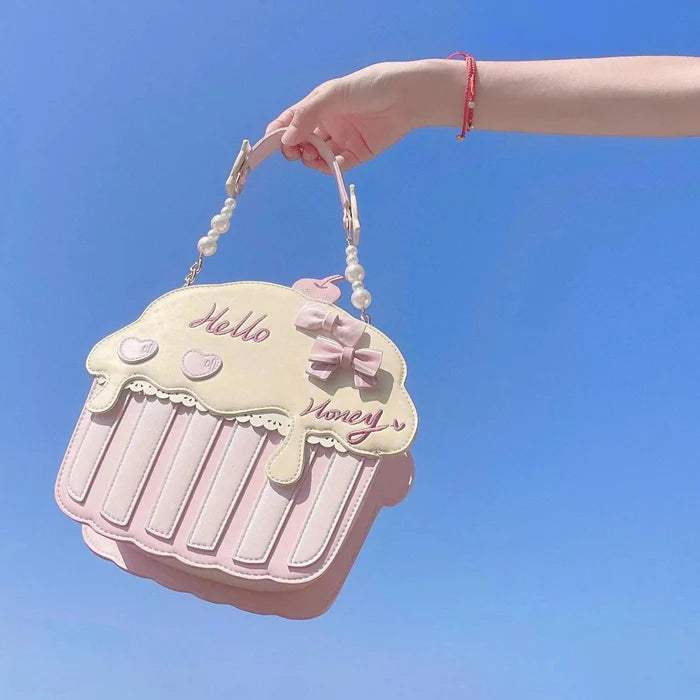 Cupcake-shaped bag with cream top and pink striped base, pearl handle and bow accent