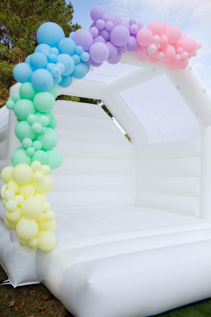 Pastel balloon garland along the corner of a white inflatable play structure