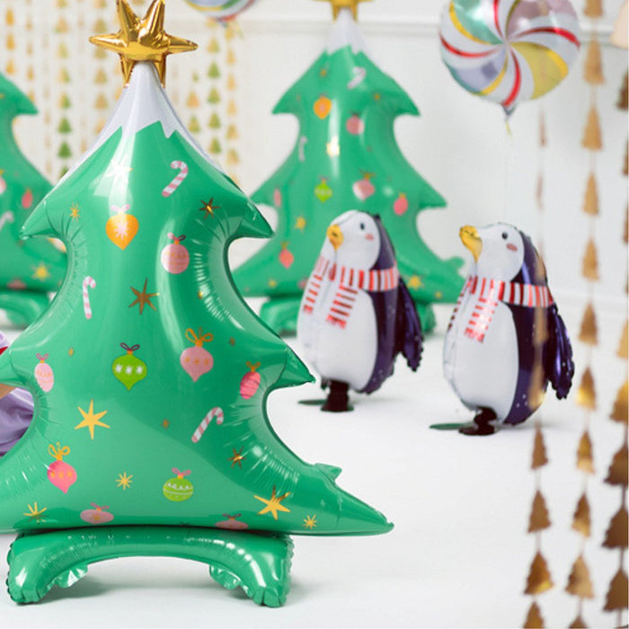 Penguin foil balloons with navy wings and red striped scarves, with a green tree balloon