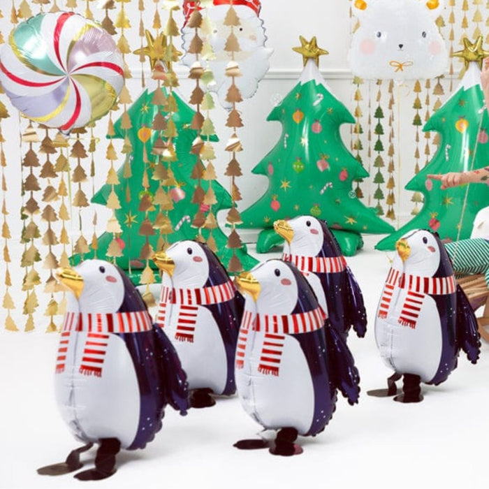 Penguin foil balloons with navy wings and red striped scarves, with a green tree balloon