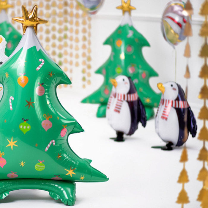 Penguin foil balloons with navy wings and red striped scarves, alongside a green tree balloon
