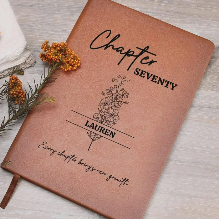Brown journal cover with “Chapter SEVENTY,” “LAUREN,” floral tree, and quote