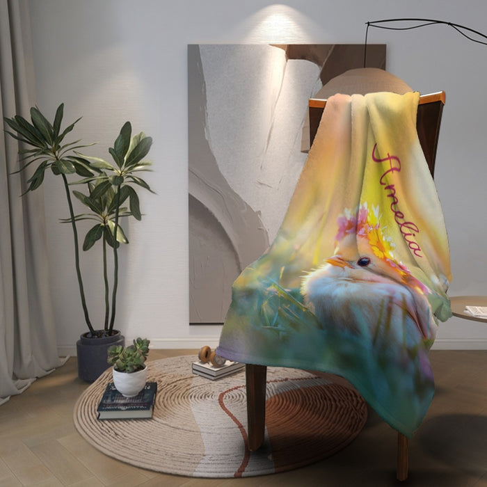 Bird-themed personalized blanket hanging on chair, showing name and flower crown