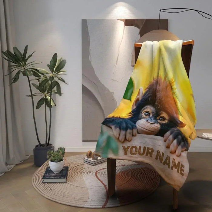 Personalized baby chimpanzee blanket draped on a chair with name 'YOUR NAME' print