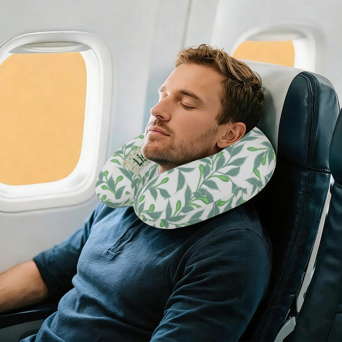 Personalized travel neck pillow with green botanical leaves, worn on an airplane seat