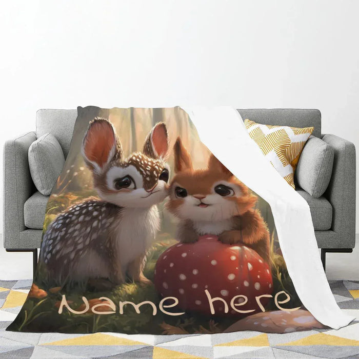 Personalized snuggle blanket draped on a sofa; bunny and deer with “Name here”