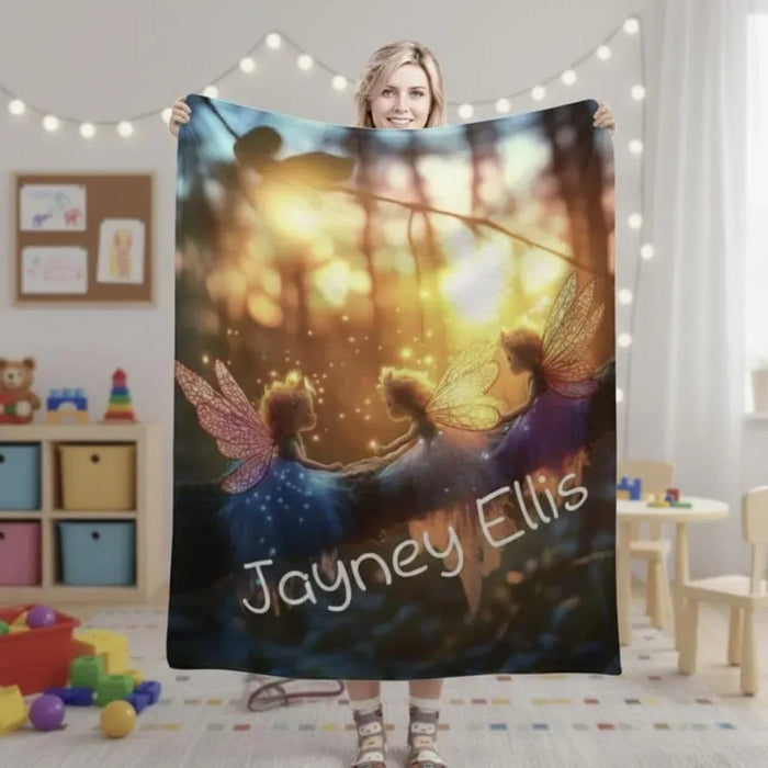 Personalized fairy throw blanket with winged figures and name text across a warm glow