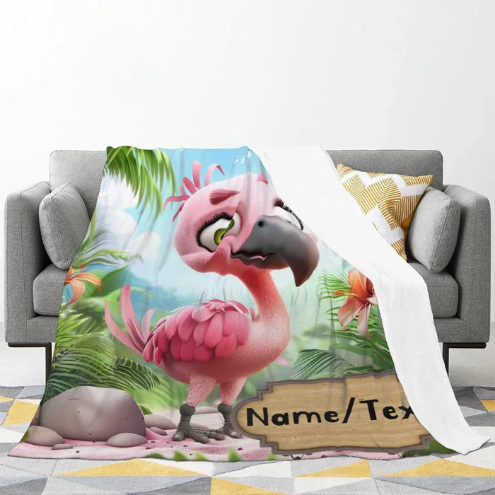 Cartoon flamingo blanket draped on gray sofa, pink and green tropical print