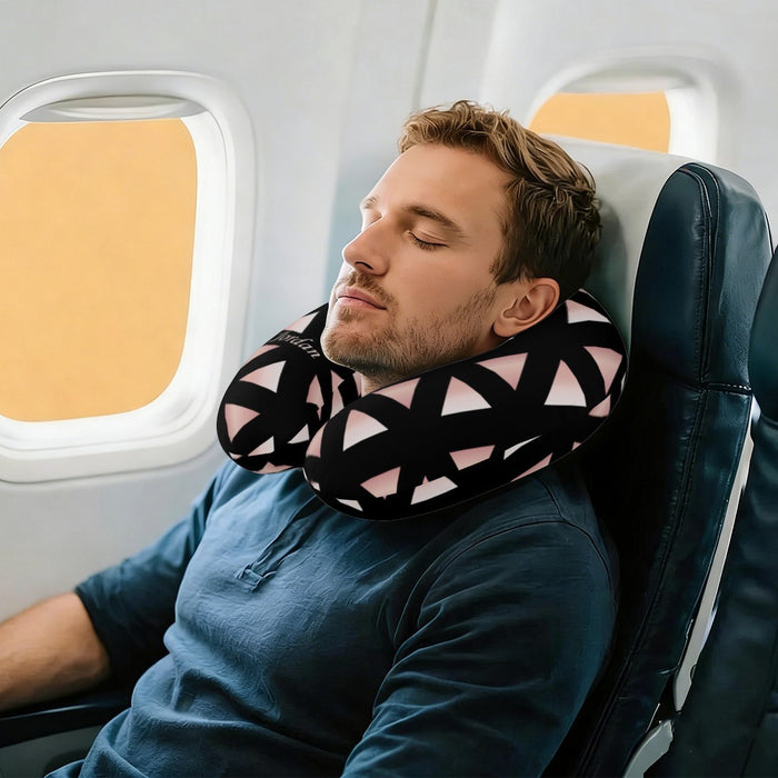 U-shaped travel neck pillow on seated man, black with pink geometric triangles, Jordan