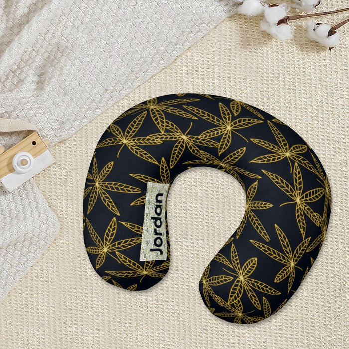 Travel neck pillow with gold botanical leaf pattern on dark navy fabric and side tag.