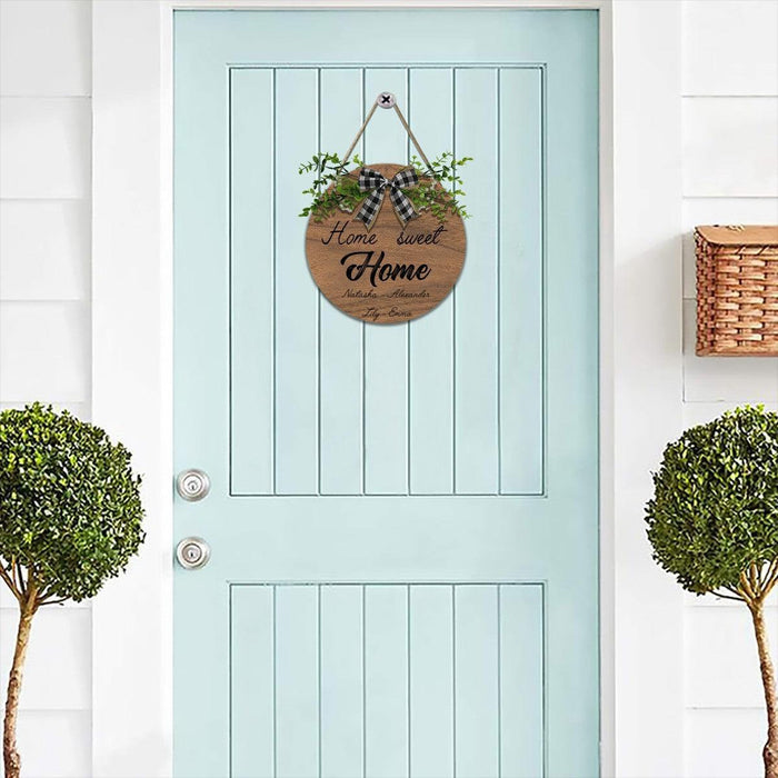 Round wooden hanging sign with rope hanger, plaid bow, and green leafy decoration