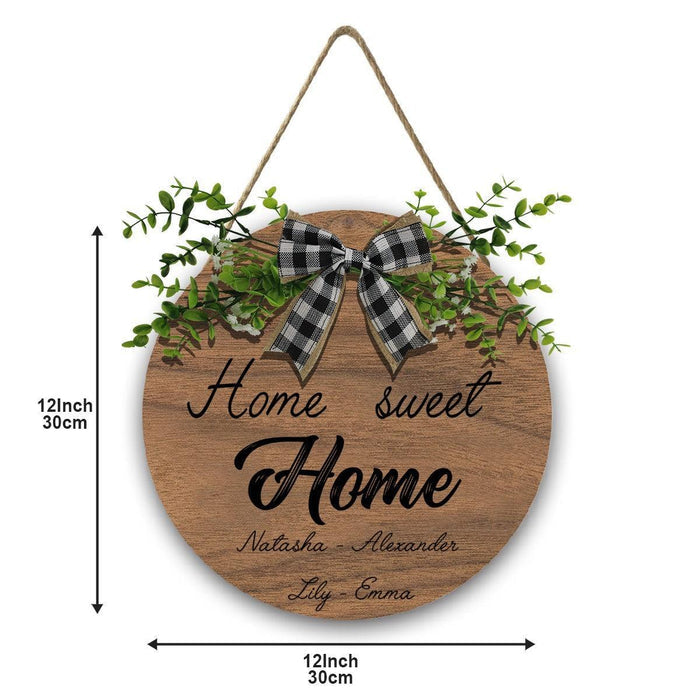 Round wooden hanging sign with plaid bow, green leaves, and “Home Sweet Home” text