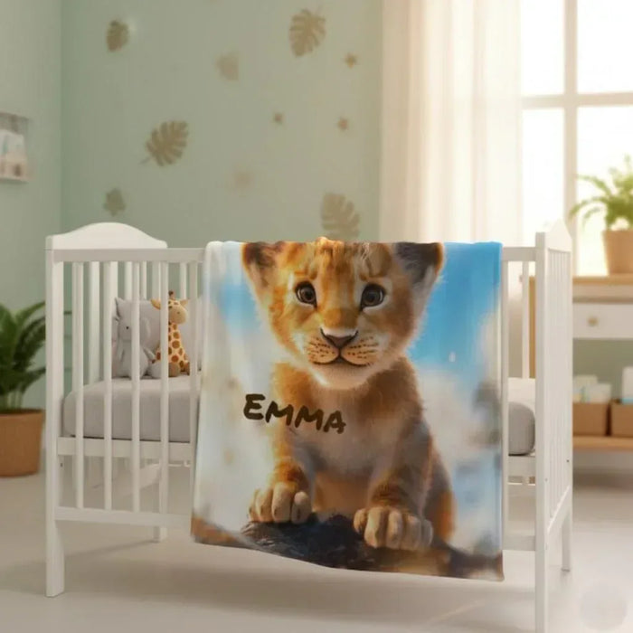 Personalized lion cub baby blanket on crib, blue background, name Emma printed in dark text