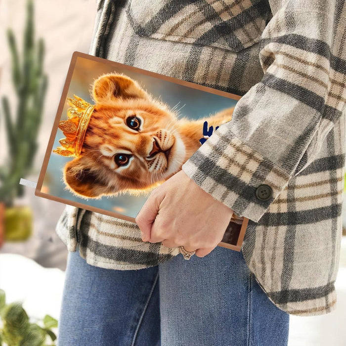 A5 notebook held in hand, showing lion cub cover with blue NAME text