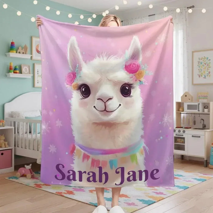 Pink fleece blanket with white llama face and ribbon scarf, custom name text