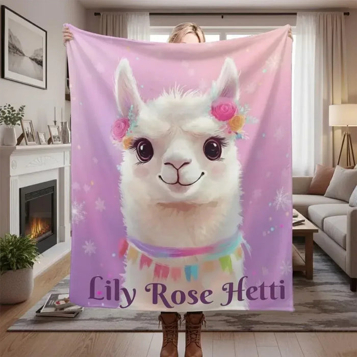 Pink fleece blanket with white llama face and custom name text, shown draped