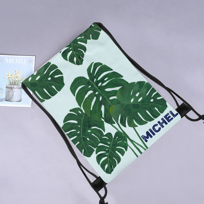 Monstera leaf drawstring tote with MICHEL name printed on light aqua fabric