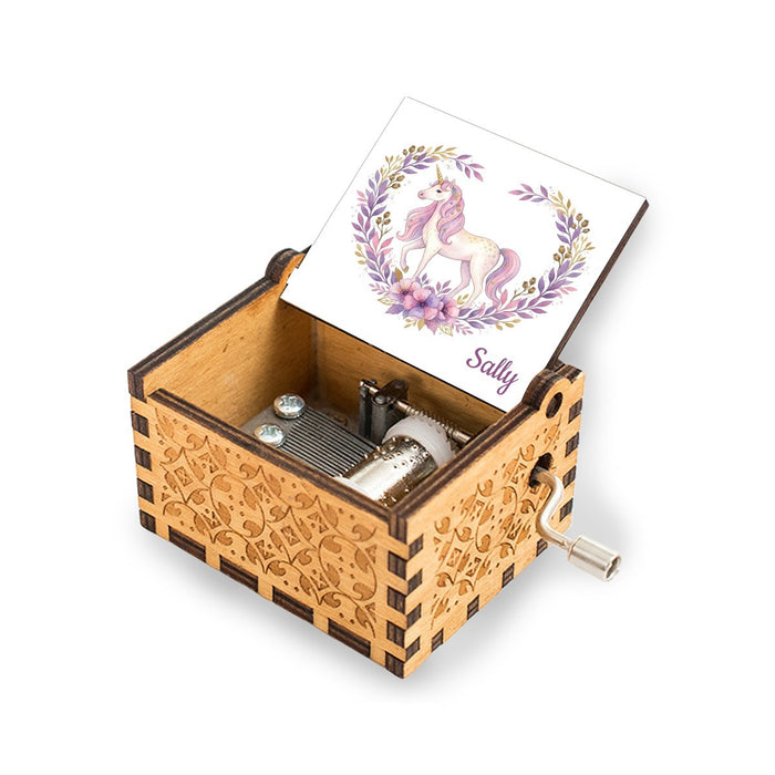 Wooden music box with open lid showing unicorn and pink flowers illustration on the top card