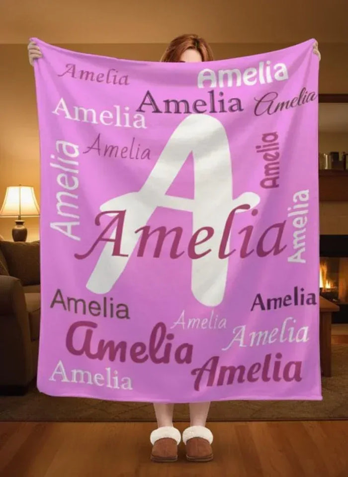 Pink fleece throw blanket with white letter A and repeated Amelia names