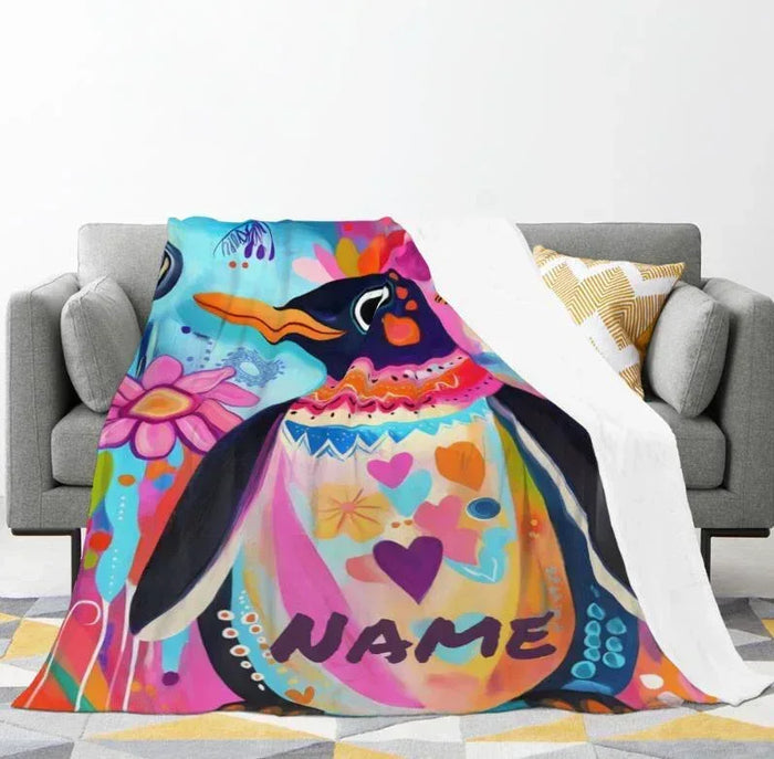 Personalized penguin blanket draped on couch, name NAME