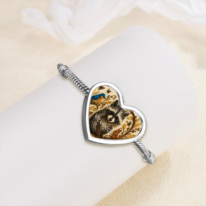 Heart-shaped raccoon bracelet charm with blue and gold artwork on silver band