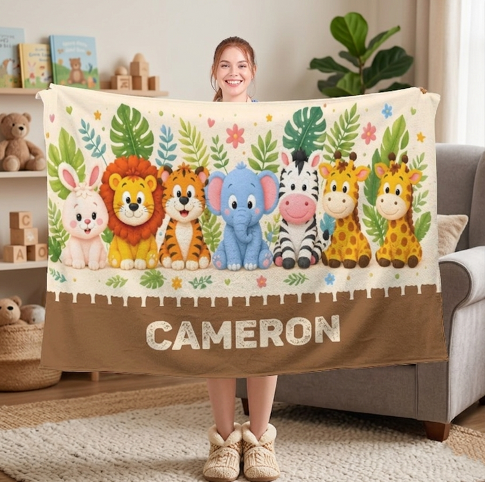 Safari animal blanket with white top, brown border, and CAMERON name, held by child