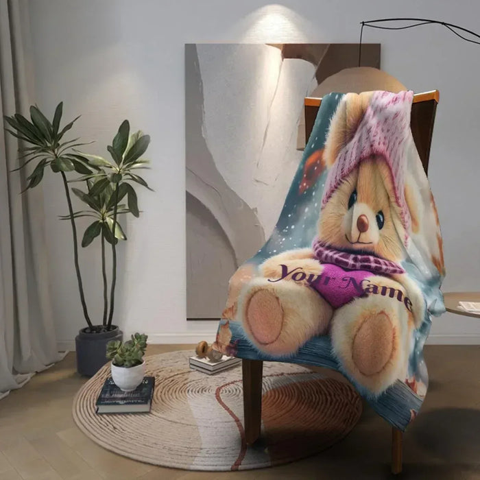 Teddy bear plush blanket draped over a chair, personalized name visible.