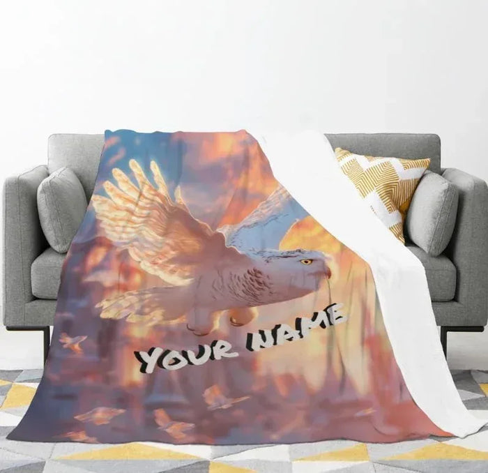 Flannel fleece throw blanket on sofa, bird artwork with clouds and 'YOUR NAME' text