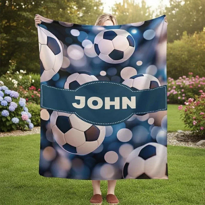 Personalized soccer throw blanket with blue ball pattern and name band reading JOHN