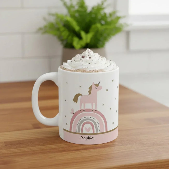 White ceramic mug with unicorn and rainbow design, topped with whipped foam, Sophia