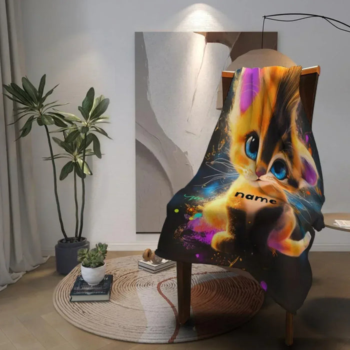 Personalized kitten blanket draped on wooden chair, colorful cat face and name