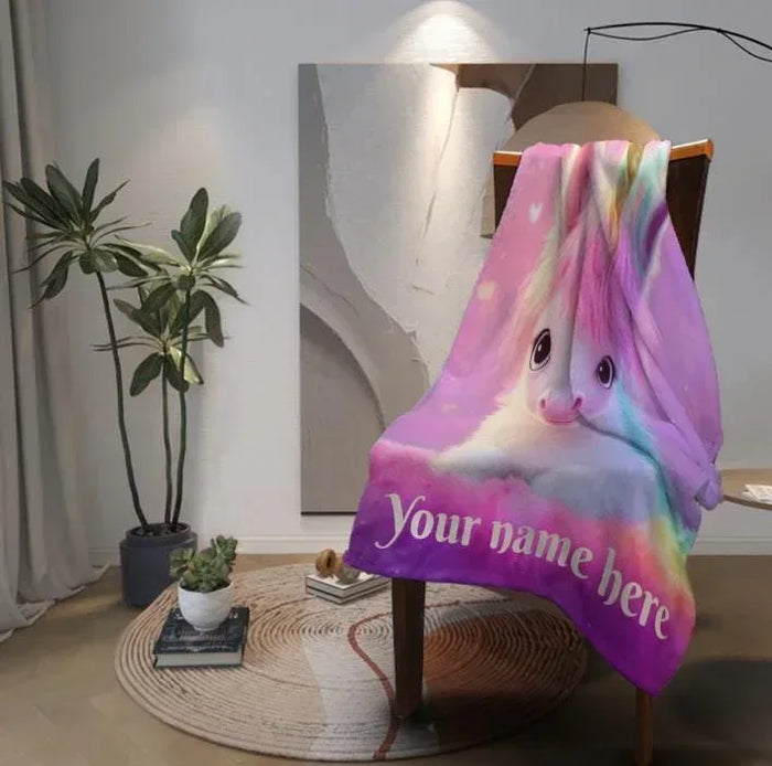 Unicorn fleece throw blanket draped on a stand, pastel rainbow mane and pink unicorn face.