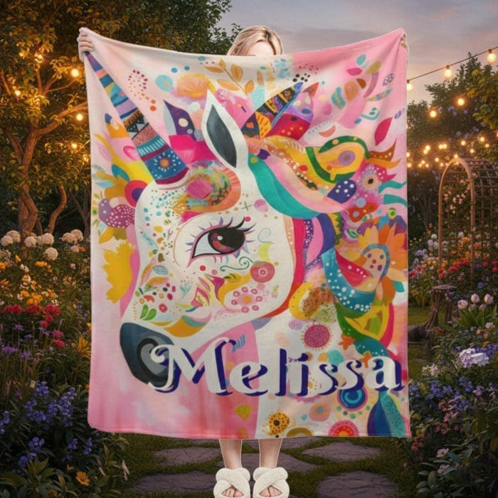 Unicorn fleece throw blanket with colorful rainbow pattern and name Melissa, held outdoors