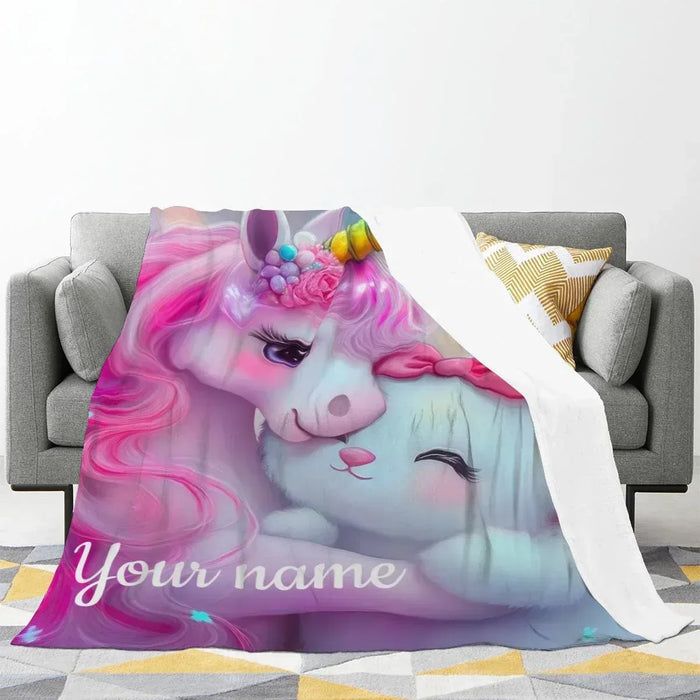 Unicorn plush blanket with 'Your name' print, draped over sofa