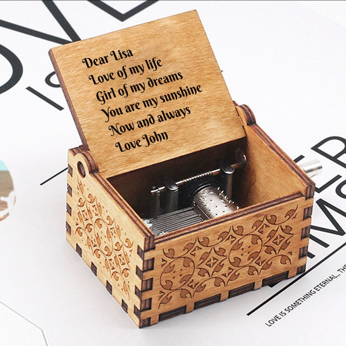 Engraved wooden music box with hinged lid text and visible music movement inside