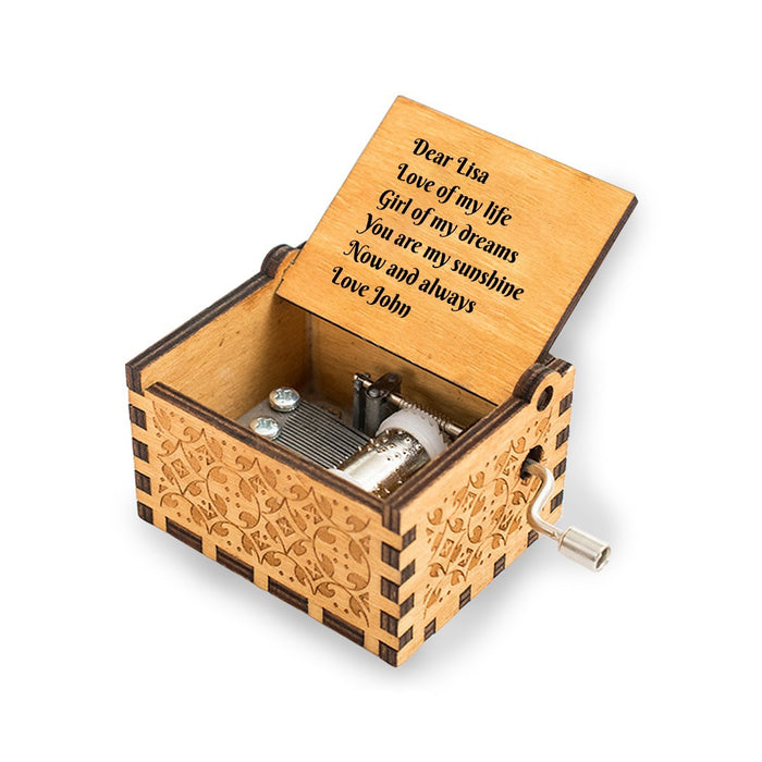 Open engraved wooden music box showing music mechanism and metal crank handle