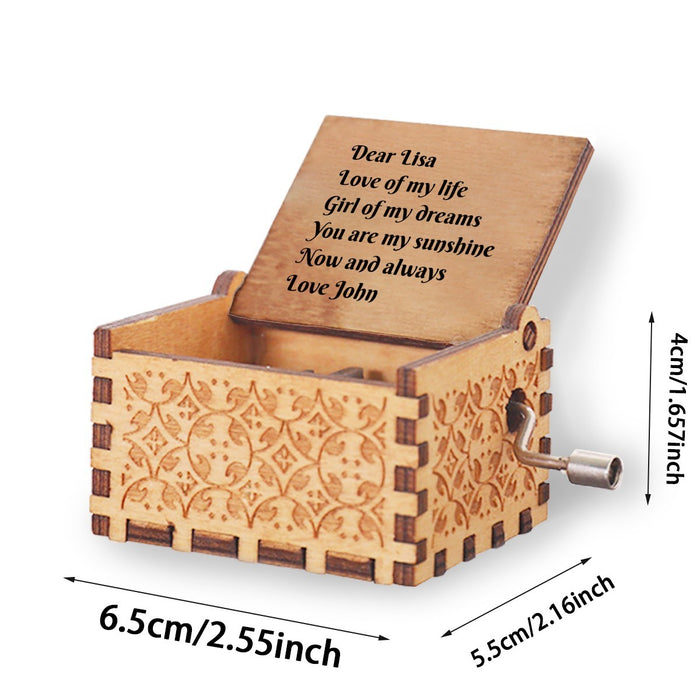 Engraved wooden music box with floral border, side crank handle, lid raised