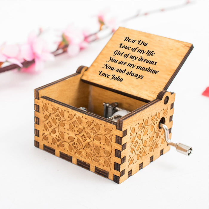 Engraved wooden music box with floral carvings and crank handle, hinged lid