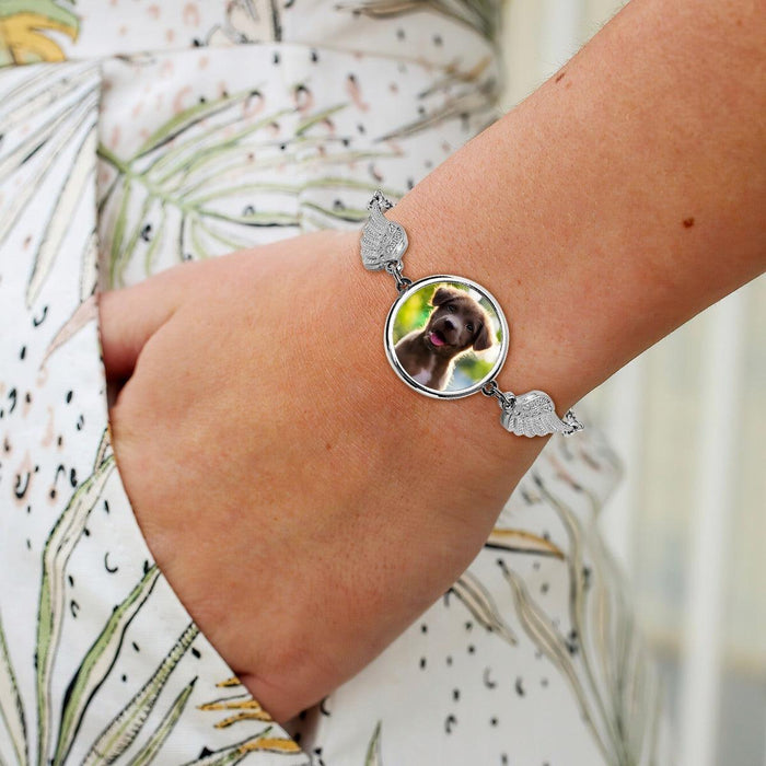 Pet memorial photo bracelet on wrist with round dog photo charm and wing accents