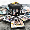 Black photo-card explosion box with a ribbon topper and scattered photo cards