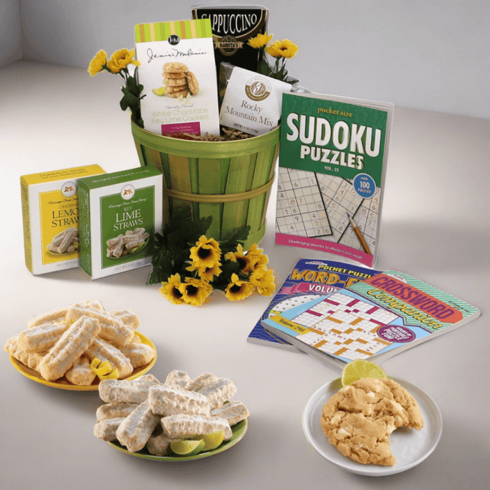 Care package gift basket with green striped bucket, assorted snacks and puzzle books.