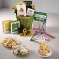 Care package gift basket with green striped bucket, assorted snacks and puzzle books.