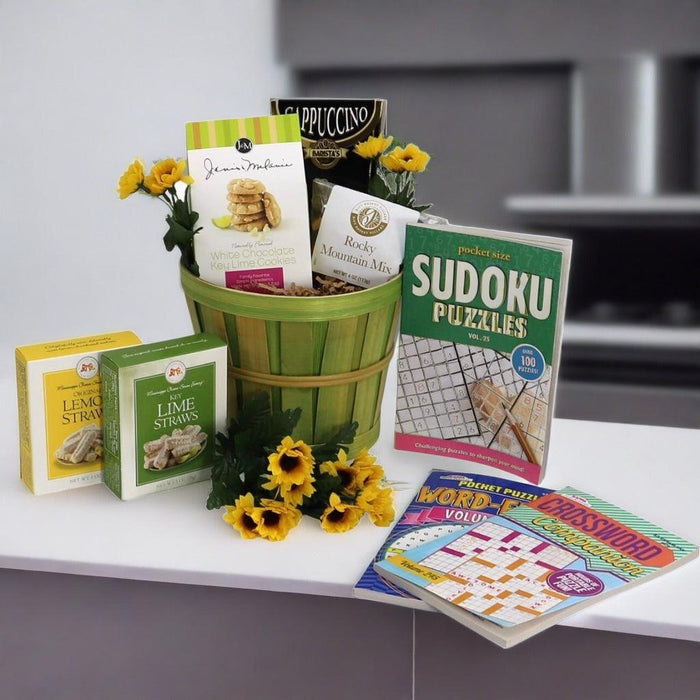 Care package gift basket with green bucket, lemon-lime snacks, and pocket puzzle games.