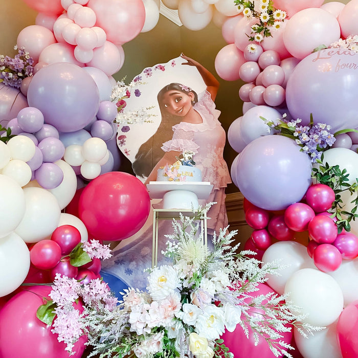 Balloon garland frame with pink, purple, and white balloons around a centerpiece