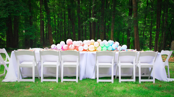 Outdoor reception balloon garland with pink and white balloons along a table