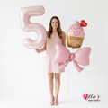 Pink bow foil balloon held with other balloons, party decoration