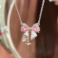 Pink bow pendant necklace with dangling star and butterfly charms on silver-tone chain