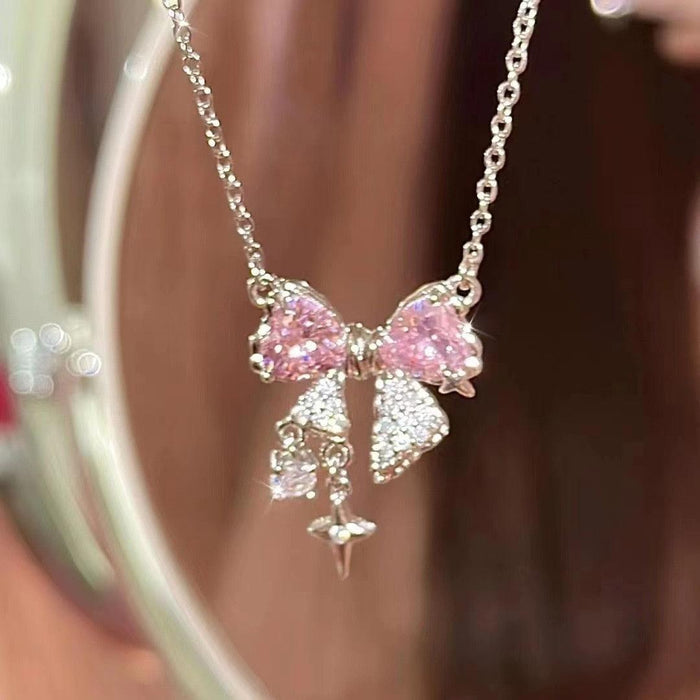 Pink bow pendant necklace with dangling star and butterfly charms on silver-tone chain