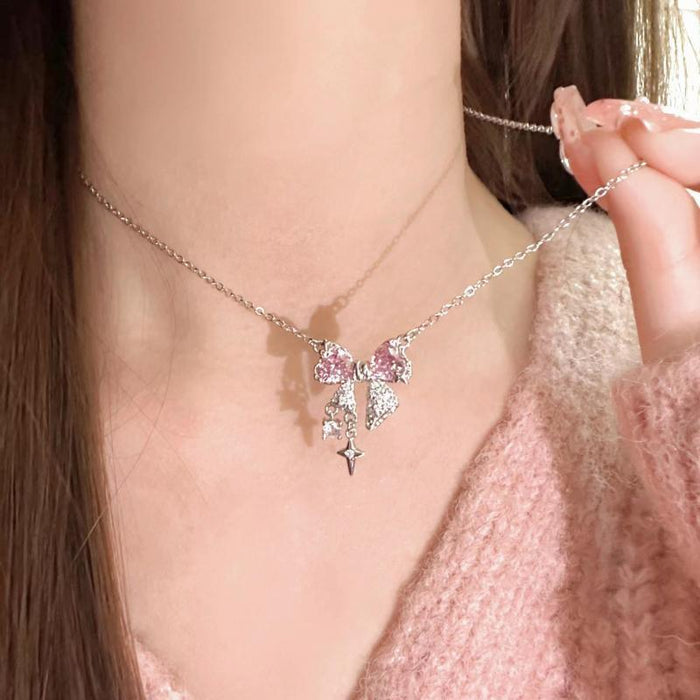 Silver-tone bow pendant necklace with pink crystal bows and small dangling cross charm