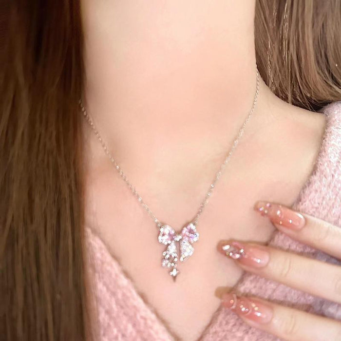 Bow pendant necklace with pink crystal center and silver-tone dangling charms